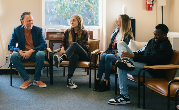 4 people talking during a therapy session about the road to recovery from addiction