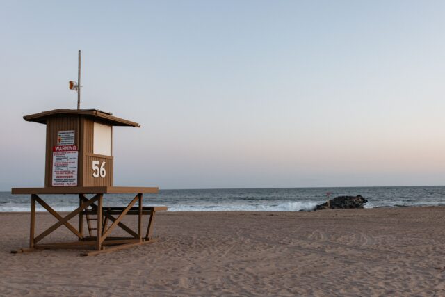 Picture of the beach with a lifeguard tower in the foreground looking over the vast sea.